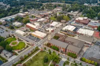 Aerial view of Lawrenceville with streets, buildings, church steeple, green park, and trees on a clear day.