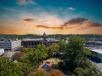 Marietta City park with fountain surrounded by trees and buildings under a colorful sunset sky.