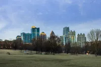 Atlanta skyline with modern skyscrapers and bare trees in a large urban park under a clear blue sky.