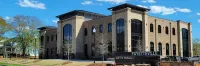Modern Fayetteville City Hall building with large windows under a blue sky with trees around.