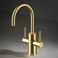 Modern matte gold kitchen faucet with dual handles on gray stone countertop and dark background.