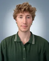 Portrait of young man with tousled blonde hair wearing a textured green polo shirt against a gradient blue background