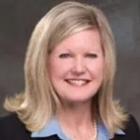 Professional headshot of a smiling woman with blonde hair in a business attire.