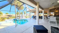 Screened patio with swimming pool, outdoor dining area, and view of palm trees and boats on the water.