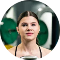 Young woman with tied-back hair working out in gym with weightlifting equipment in the background