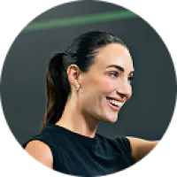 Smiling woman with ponytail wearing black sleeveless shirt in a fitness setting
