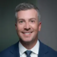 Smiling middle-aged man in business suit with gray hair against a plain background