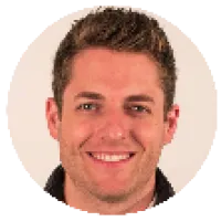 Smiling young man with short brown hair wearing a black jacket, beige background