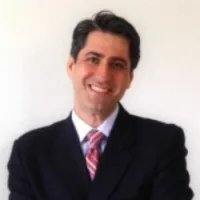 Smiling man in a suit with a light background, showcasing professionalism and confidence.