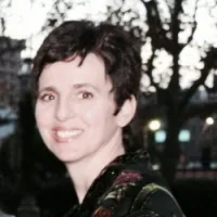 Smiling woman in vibrant attire against a soft-focus sunset background.