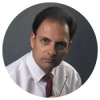 Portrait of a serious man in white shirt and red patterned tie against a dark background holding eyeglasses.