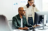 A diverse team collaborating at a computer in a modern office environment, showcasing teamwork and productivity.