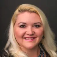 Smiling blonde woman with light makeup and dark eyes against a black background