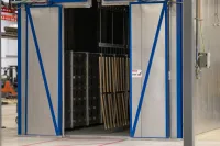 Industrial doors open to reveal a stacking area with wooden pallets inside a modern warehouse.
