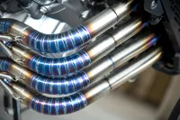 Close-up of polished exhaust pipes showcasing vibrant blue and silver finishes on a high-performance engine.