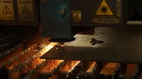 Industrial laser cutting machine slicing through metal sheet, producing bright sparks and heat.