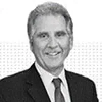 Black and white portrait of a smiling middle-aged man in a suit and tie with short gray hair.