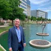 a man standing in front of a pond with a fountain in it