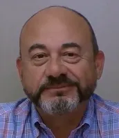 Middle-aged man with a bald head, salt-and-pepper beard, and plaid shirt against a neutral background.