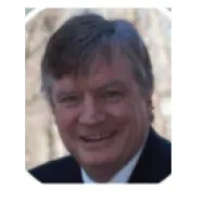 Smiling middle-aged man in suit outdoors with blurred natural background, close-up portrait.