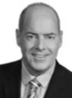 Portrait of a smiling bald man in a suit and patterned tie against a white background