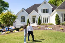 a man and a woman standing in front of a house