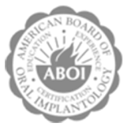 Black and white badge logo of the American College of Oral Implantologists with sun and text in circle.