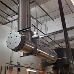 Industrial ducting system with large metal pipes and supports inside a commercial building ceiling.
