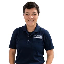 Smiling person wearing navy polo shirt with Property Masters logo on pocket against transparent background