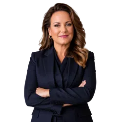 Confident businesswoman with crossed arms wearing a navy blazer and gold hoop earrings smiling at camera.