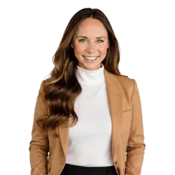 Smiling woman with long wavy hair wearing a white turtleneck and camel blazer, isolated on transparent background