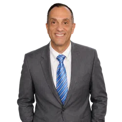Smiling middle-aged man in gray suit with blue striped tie and white shirt, posing against white background.