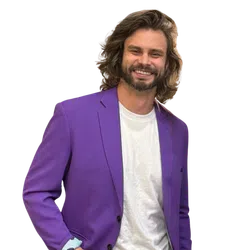 Smiling man with long hair wearing a purple blazer over a white t-shirt against a transparent background
