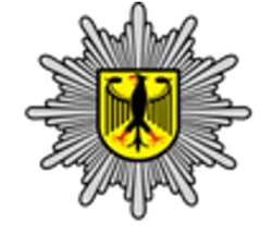 Federal Police emblem with a golden eagle on a yellow shield, radiating starburst design.