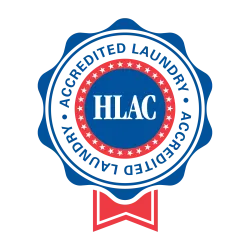 Blue and red badge with stars and ribbon labeled HLAC Accredited Laundry certification seal