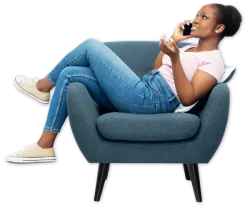 Young woman in casual clothes reclining on blue armchair talking on smartphone and smiling