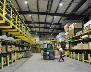 Spacious warehouse with tall yellow shelving, stocked with wood materials and a worker beside a forklift.