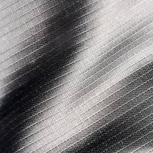 Close-up of textured gray fabric with fine woven patterns and light shadows creating depth and gradient.