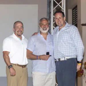 Three men smiling together at an event, showcasing camaraderie and celebration.