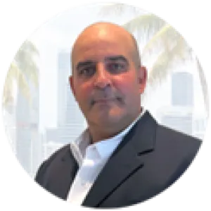 Professional man in a dark suit with a white shirt, city skyline and palm trees in the background.