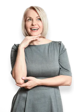 Smiling blonde woman in gray dress posing with hand under chin looking upward thoughtfully.