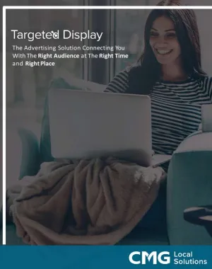 a woman sitting at a table with a laptop and smiling at the camera