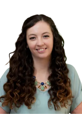 Smiling young woman with long curly hair wearing a light green top and colorful statement necklace.