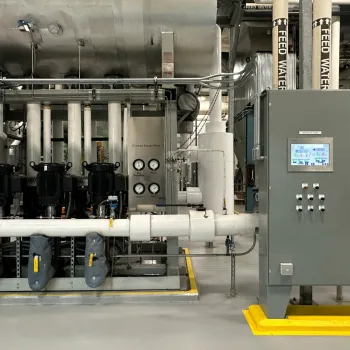 Industrial energy plant with control panels, pipes, gauges, pumps, and labeled feed water system indoors
