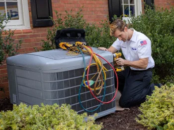 Technician servicing an air conditioning unit outside a home with tools and equipment.