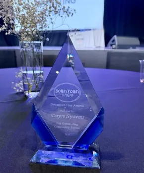 Blue glass award for Dayco Systems as Outstanding Community Partner at Downtown First Awards 2026 on a blue table.