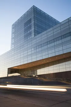 Modern glass building with sleek design and light trails from passing vehicles at dusk in urban setting