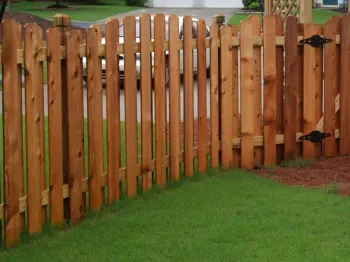 A wooden picket fence enclosing a lush green lawn, featuring natural wood tones and a sturdy design.