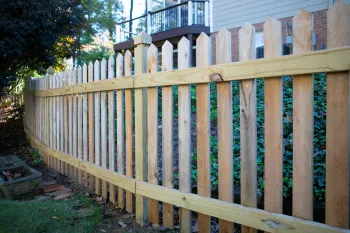 Curved wooden picket fence surrounding a backyard garden, adding charm and security to the outdoor space.