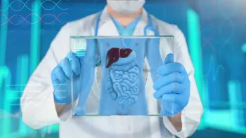 Doctor wearing gloves and a mask holding a transparent display showing digestive system anatomy with liver and intestines.
